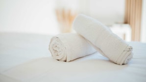 A neatly made bed with white linens and a rolled towel on top. - Studio centre-ville Rennes proche Gare (Rennes)
