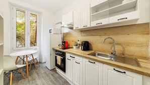A compact kitchen with white cabinets, a wooden countertop, a sink, and a coffee maker. - Studio centre-ville Rennes proche Gare (Rennes)