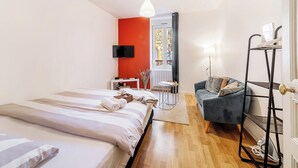 A modern hotel room with a bed, a sofa, a TV, and a balcony with a view. - Studio centre-ville Rennes proche Gare (Rennes)