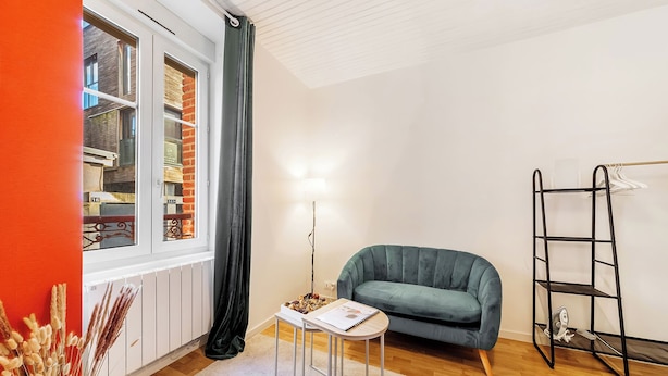 A modern living room with a sofa, a small table, a floor lamp, and a ladder against the wall. - Studio centre-ville Rennes proche Gare (Rennes)