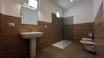 Un bagno moderno con lavabo su piedistallo, cabina doccia in vetro e servizi igienici.