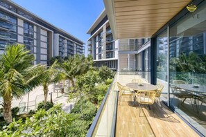 Un bâtiment moderne doté de nombreux balcons, d’un espace extérieur aménagé et d’une végétation luxuriante.