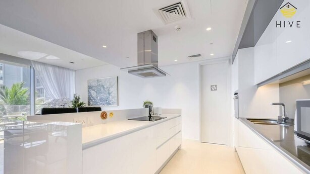 Een moderne keuken met een groot kookeiland, roestvrijstalen apparatuur en uitzicht op de omgeving.