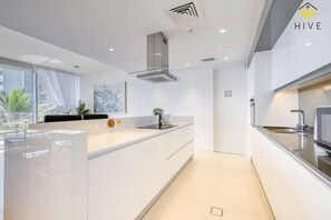 A modern kitchen with a large island, stainless steel appliances, and a view of the outdoors. - Bluewaters Island Oceanview Apt w/ Balcony & Pool (Dubai)