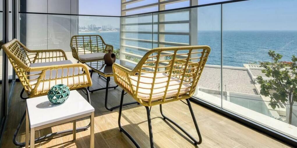 A balcony with wicker furniture and a view of the sea.