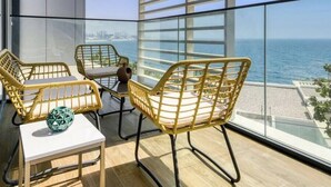 Een balkon met rieten meubilair en uitzicht op zee.