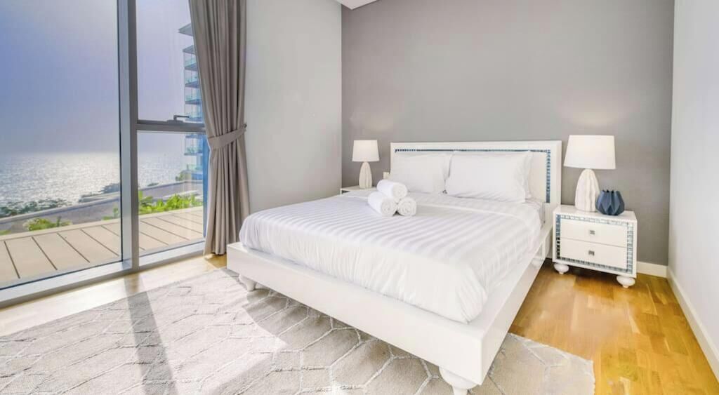 Een moderne slaapkamer met een groot bed, twee nachtkastjes en uitzicht op de oceaan.