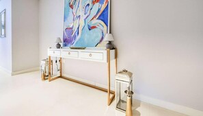 Une console blanche, ornée de deux lampes, d’un tableau et d’une lanterne.