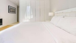Een slaapkamer met een groot bed, een kledingkast en een nachtkastje.