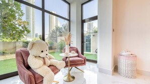 Une chambre moderne avec une grande fenêtre, un fauteuil confortable, une petite table et un panier en osier.