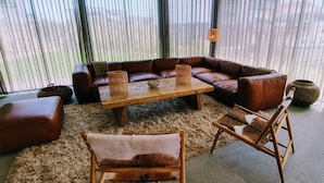 Ein modernes Wohnzimmer mit einer ledernen Eckcouch, einem Holztisch und zwei Holzstühlen.