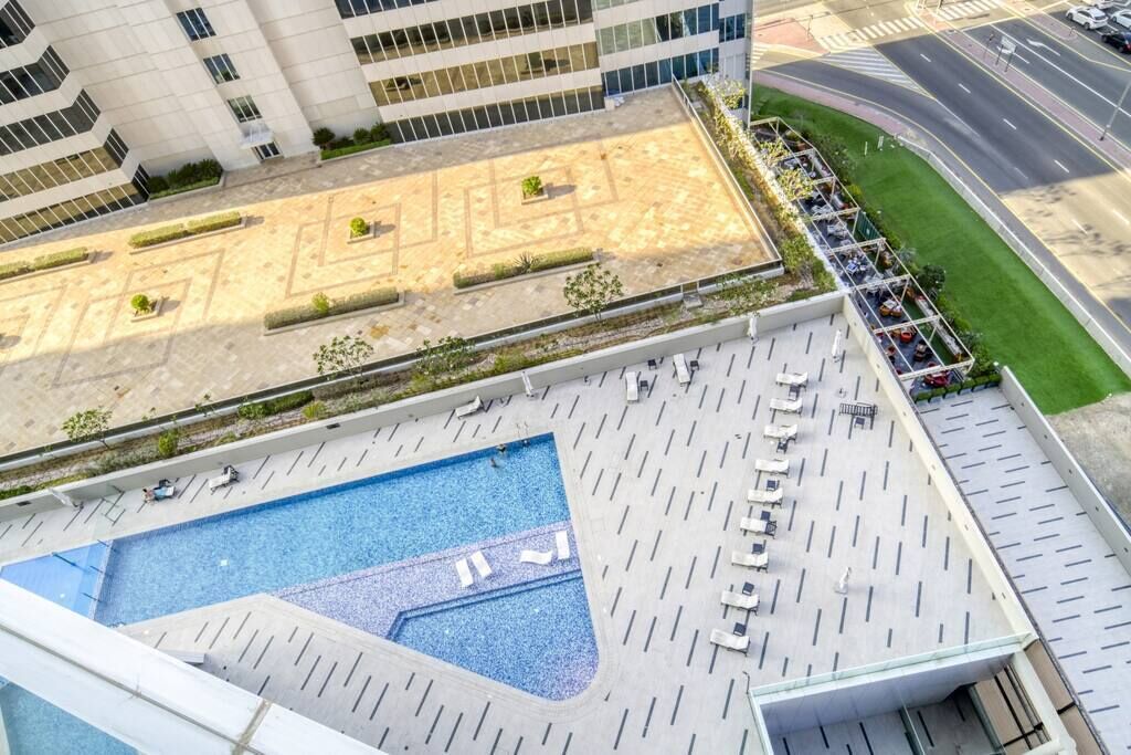 Un espace piscine aménagé sur le toit, avec des chaises longues et une piscine.