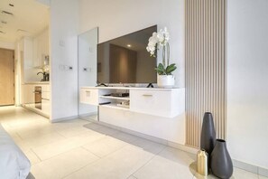 A modern bedroom with a large mirror, a bedside table, and a potted orchid. - Beach View Studio Walk to Metro & Dubai Mall (Dubai)