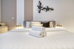 A hotel room with a large bed, two bedside lamps, a wall art piece, and a chair. - Beach View Studio Walk to Metro & Dubai Mall (Dubai)
