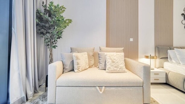 Une chambre moderne avec un canapé-lit, une table de chevet, une lampe et une plante en pot.