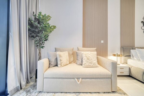Un dormitorio moderno con sofá cama, una mesita de noche, una lámpara y una planta en maceta.