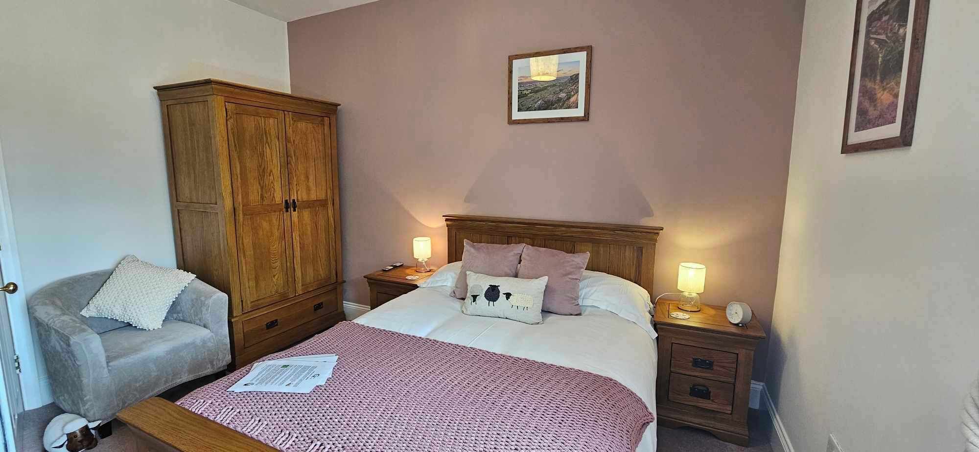 Une chambre à coucher comprenant un lit, des tables de chevet, une armoire en bois, une chaise et un tableau encadré accroché au mur.