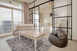 A modern living room with a sofa, a coffee table, a bean bag, and a patterned rug.