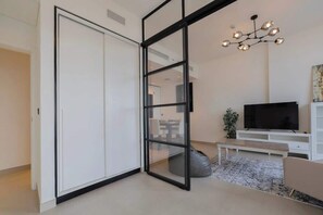 Un salon moderne doté d’une porte-fenêtre coulissante, d’un téléviseur à écran plat, d’un banc et d’un luminaire décoratif.
