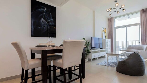A modern living room with a dining table, chairs, a sofa, a bean bag, a TV, and a large window with curtains.