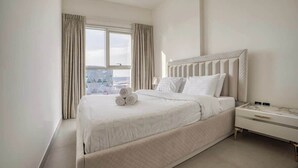 A hotel room with a large bed, a nightstand, and a window with curtains.