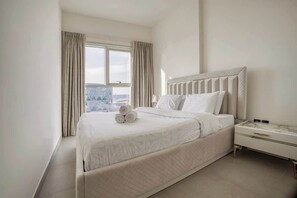 A hotel room with a large bed, a nightstand, and a window with curtains.