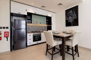Una cocina moderna con horno empotrado, refrigerador y un comedor con mesa y sillas.