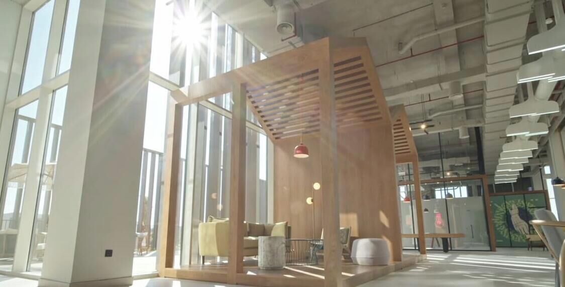 Un intérieur moderne avec de grandes fenêtres, un séparateur en bois et des espaces aménagés pour s’asseoir.
