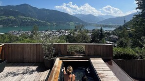 A wooden deck with a hot tub overlooking a scenic lake and mountains. - Wanna Rise Studio (Zell am See)