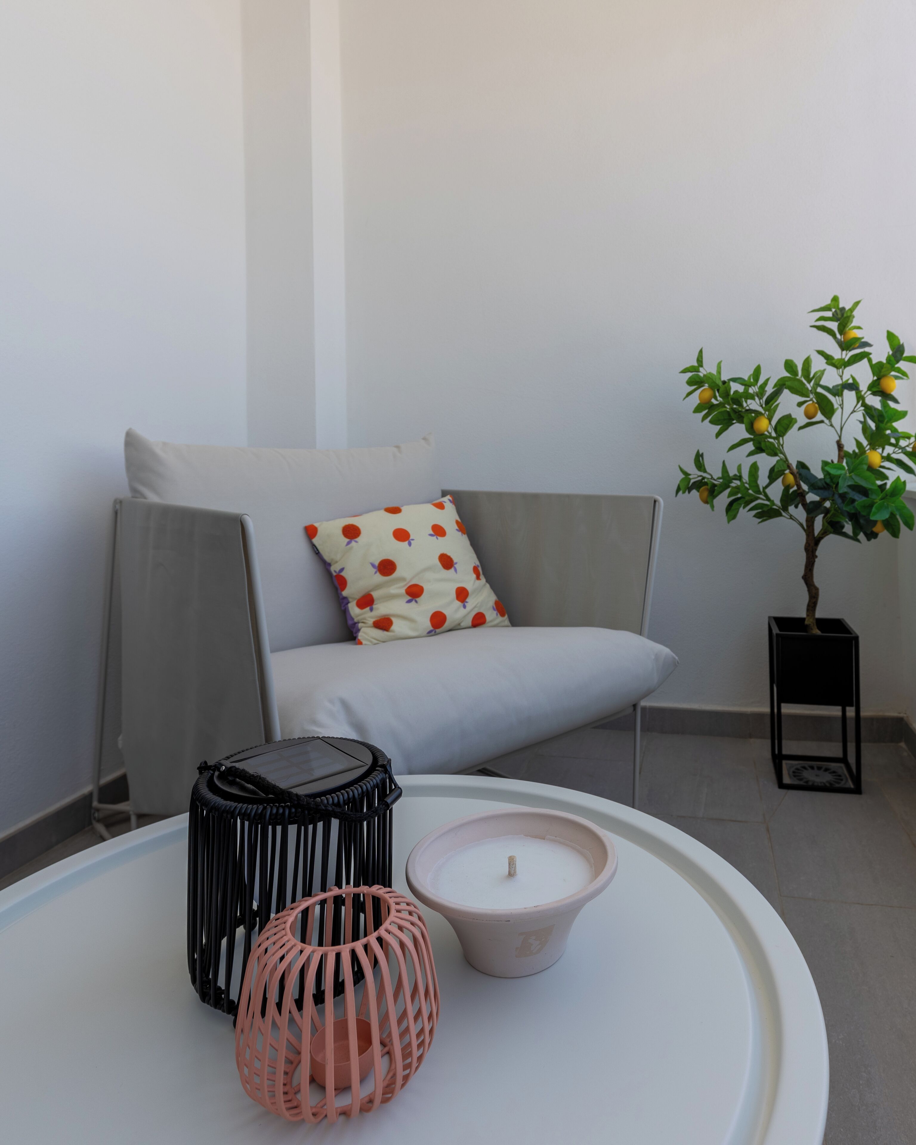 A modern living room with a grey sofa, a small potted plant, and a white round table with decorative items.