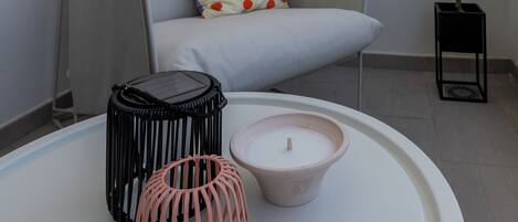 A modern living room with a grey sofa, a small potted plant, and a white round table with decorative items.
