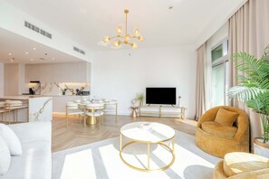 A modern living room with a round coffee table, a sofa, a TV, and a dining area with chairs and a table.