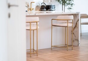 A kitchen with two bar stools, a marble countertop, and a wooden floor.