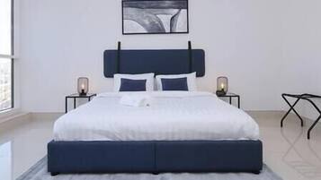 A modern bedroom with a large bed, two bedside tables, and a wall-mounted artwork.