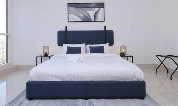 Une chambre moderne avec un grand lit, deux tables de chevet et une œuvre d’art accrochée au mur.