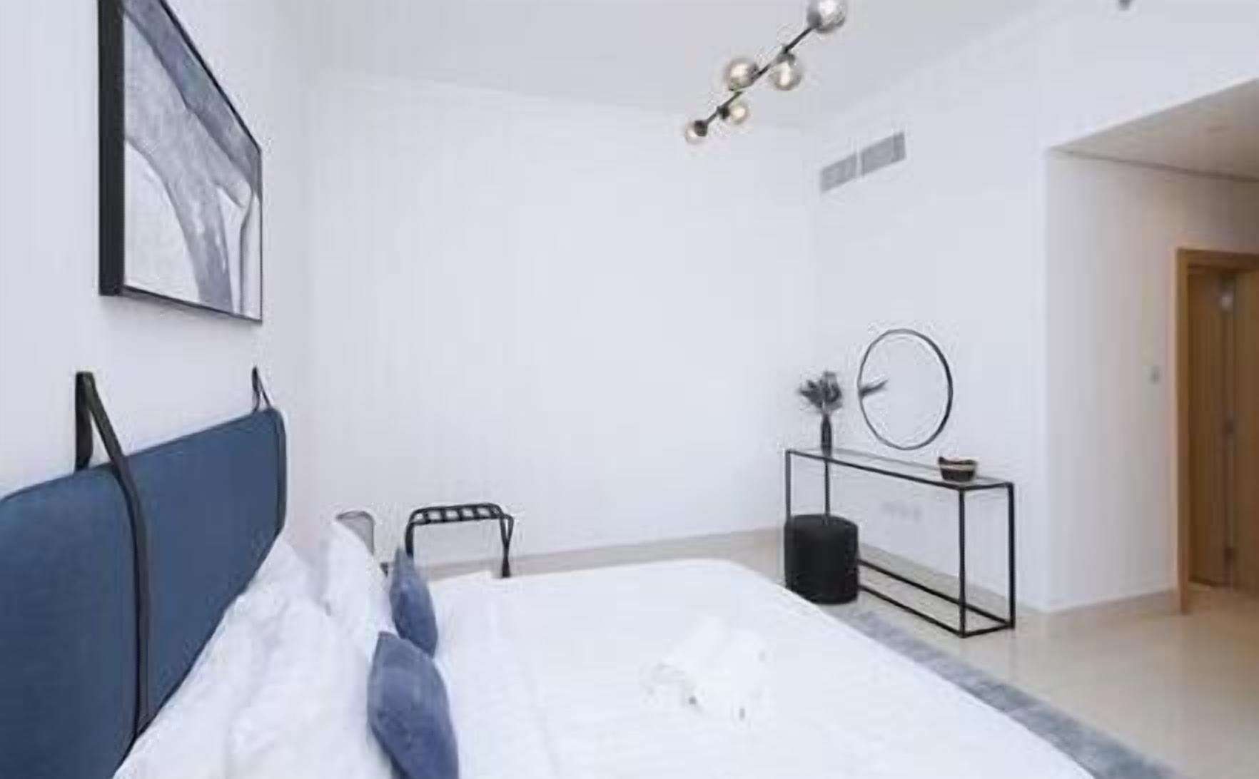 Un dormitorio con cama, mesita de noche, un reloj de pared y un cuadro enmarcado.