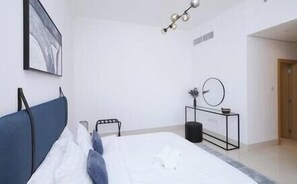 Quarto com cama, mesa de cabeceira, relógio de parede e quadro emoldurado.