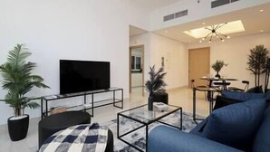 Un salon moderne doté d’un téléviseur à écran plat, d’un canapé, d’une table basse et d’un coin repas avec une table et des chaises.