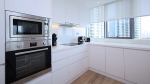 Een moderne keuken met inbouwapparatuur, een raam met uitzicht op de stad en witte kasten.