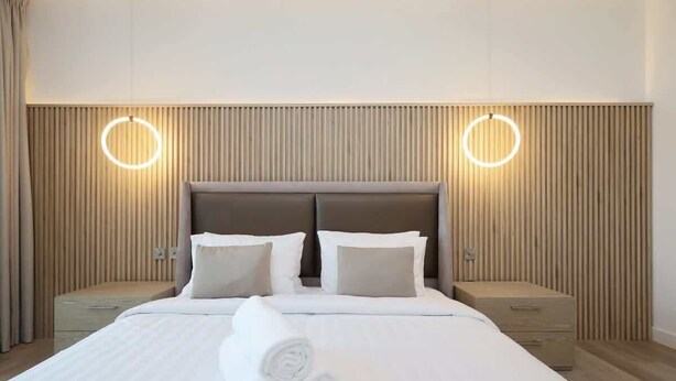Hotelkamer met een bed, twee nachtkastjes, een hoofdeinde en twee wandlampen.