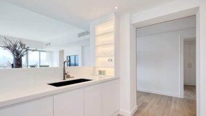 Een moderne keuken met witte kastjes, een zwarte spoelbak en een ingebouwde plankunit.