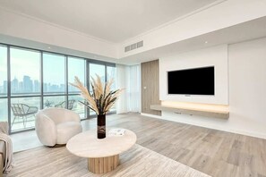 Una sala de estar moderna con un ventanal grande, un televisor de pantalla plana y una mesa de centro redonda.