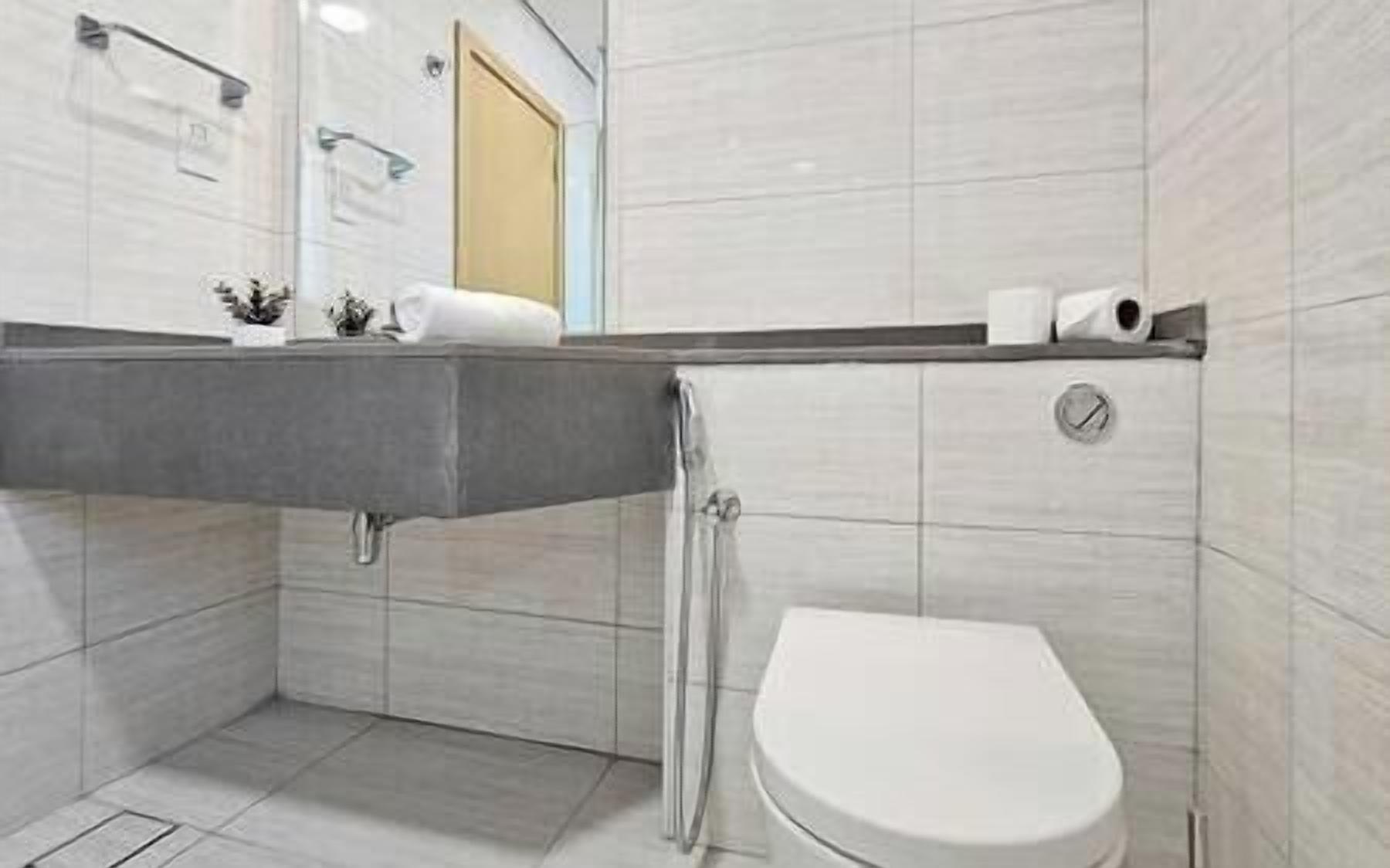 Moderni kylpyhuone, jossa on sisäänrakennettu pesuallas, wc ja suihku.