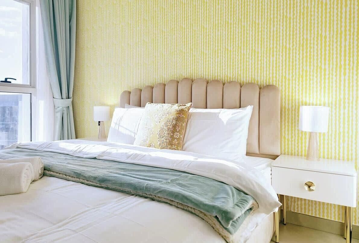 Una camera d'albergo con un letto, un comodino e una finestra con tende.