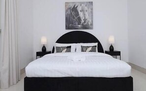 Ein Bett mit schwarzem Kopfteil, weißer Bettwäsche und zwei Nachttischlampen.
