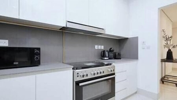 A modern kitchen with white cabinets, a stove, and a microwave.
