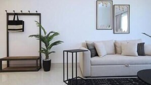 A living room with a sofa, a coffee table, a potted plant, and a wall-mounted mirror.