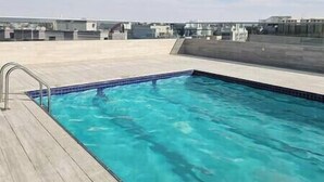 A rectangular swimming pool with a tiled edge, surrounded by a wooden deck.