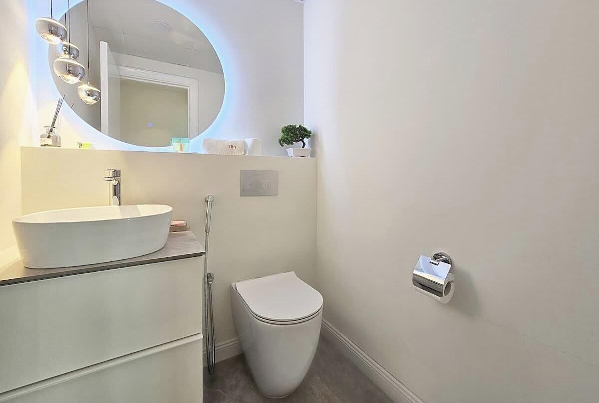 A modern bathroom with a white sink, mirror, and toilet.