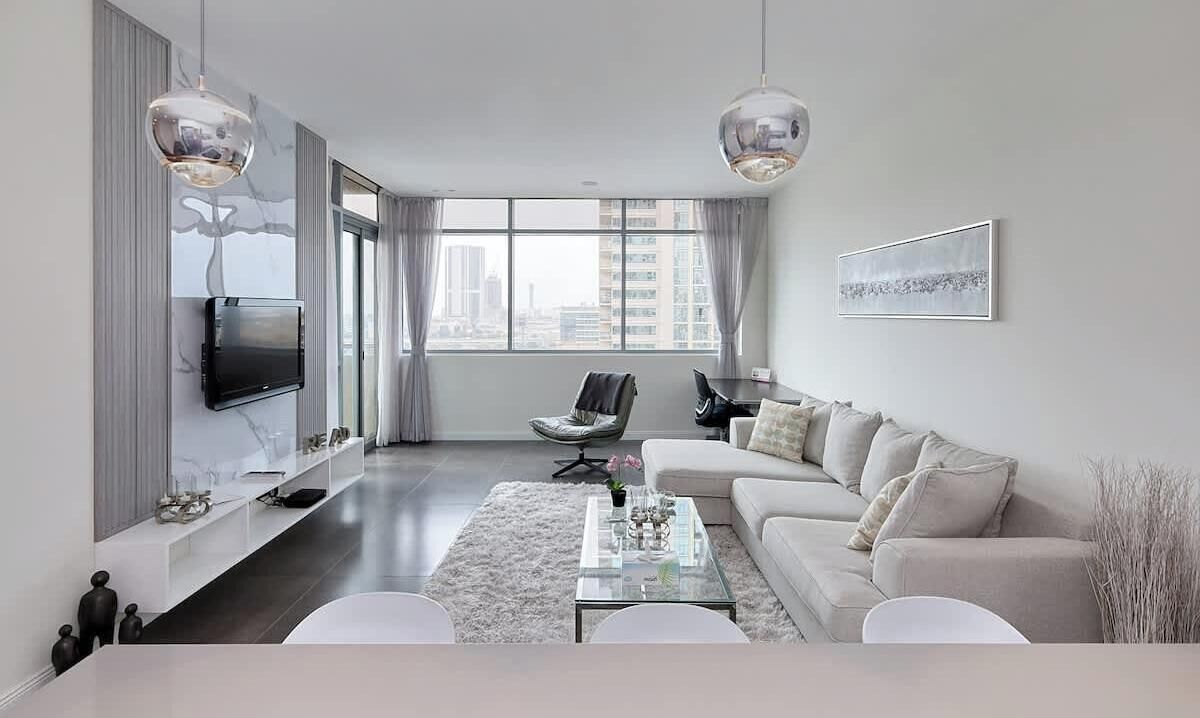 Una sala de estar moderna con un televisor de pantalla plana, un sofá, una mesa de centro y una silla.